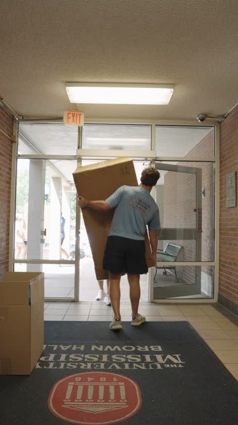 A crew member carrying a furniture box through the front door of Brown Hall at the University of Mississippi