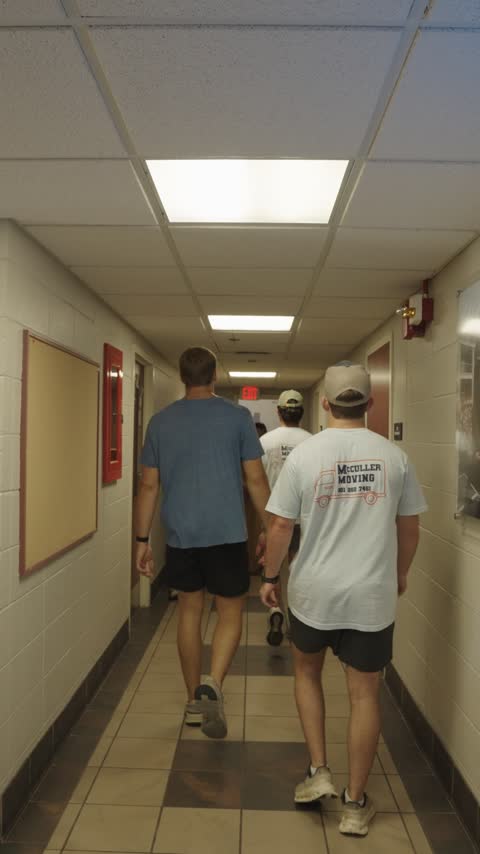 Crew members in McCuller Moving shirts heading down a residence hall corridor on move-in day