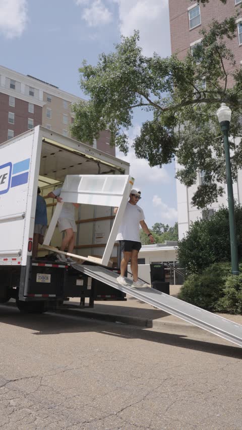 The crew walking a white bookcase down the truck ramp outside an Ole Miss residence hall