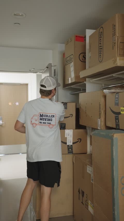A crew member stacking shipped packages and storage bins in the receiving room