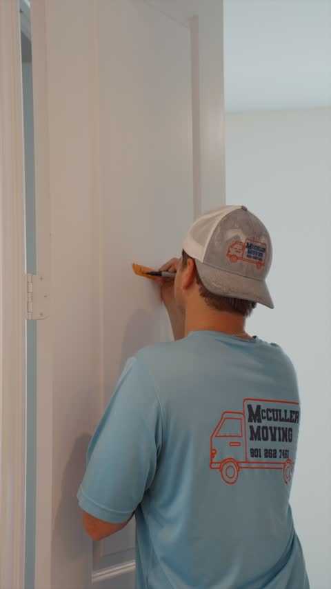 A crew member in a McCuller cap making a small fix to a door on delivery day