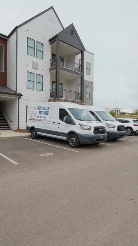 Two McCuller Moving vans parked outside a student apartment building