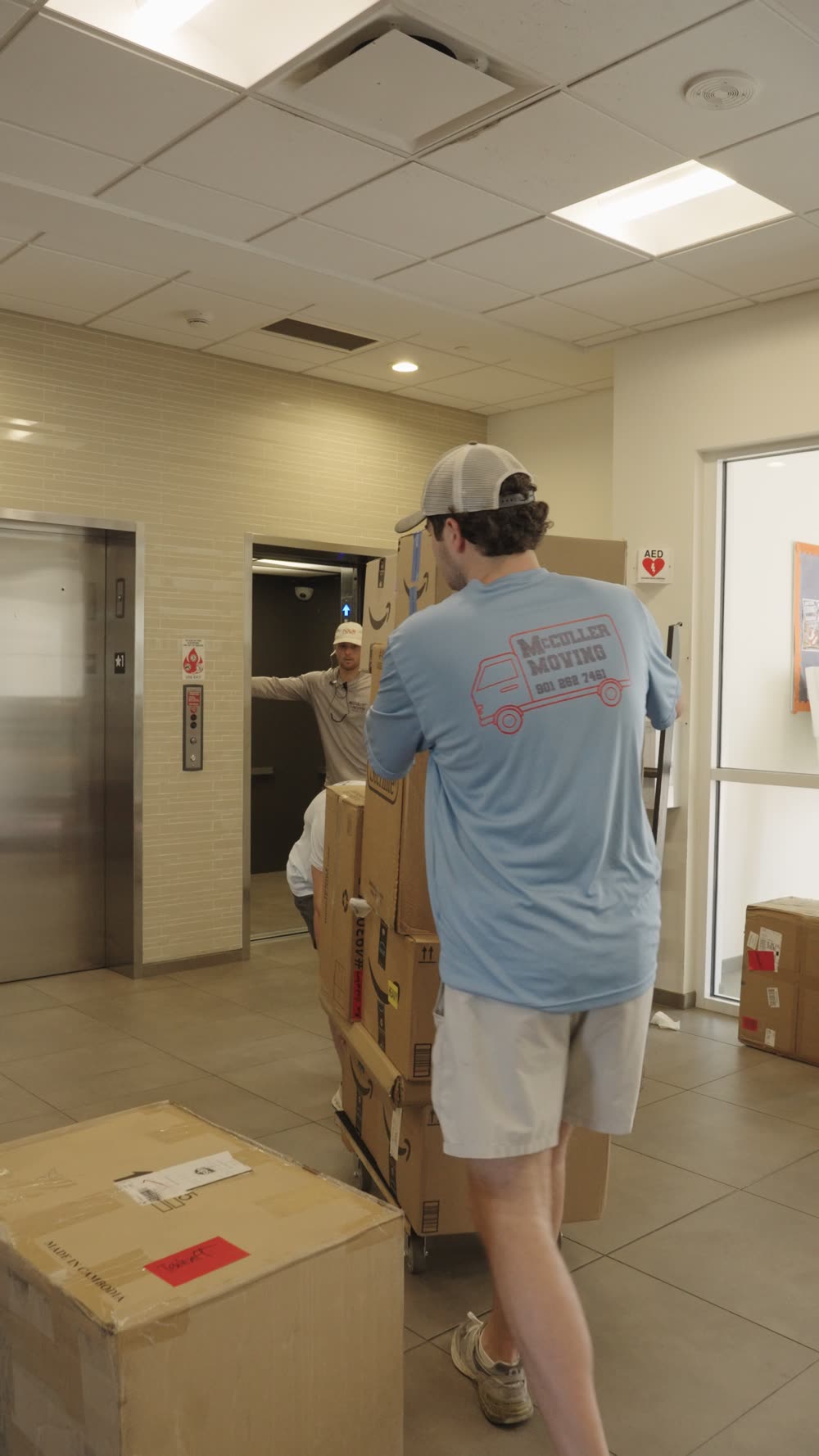 Crew moving boxes through a residence hall corridor