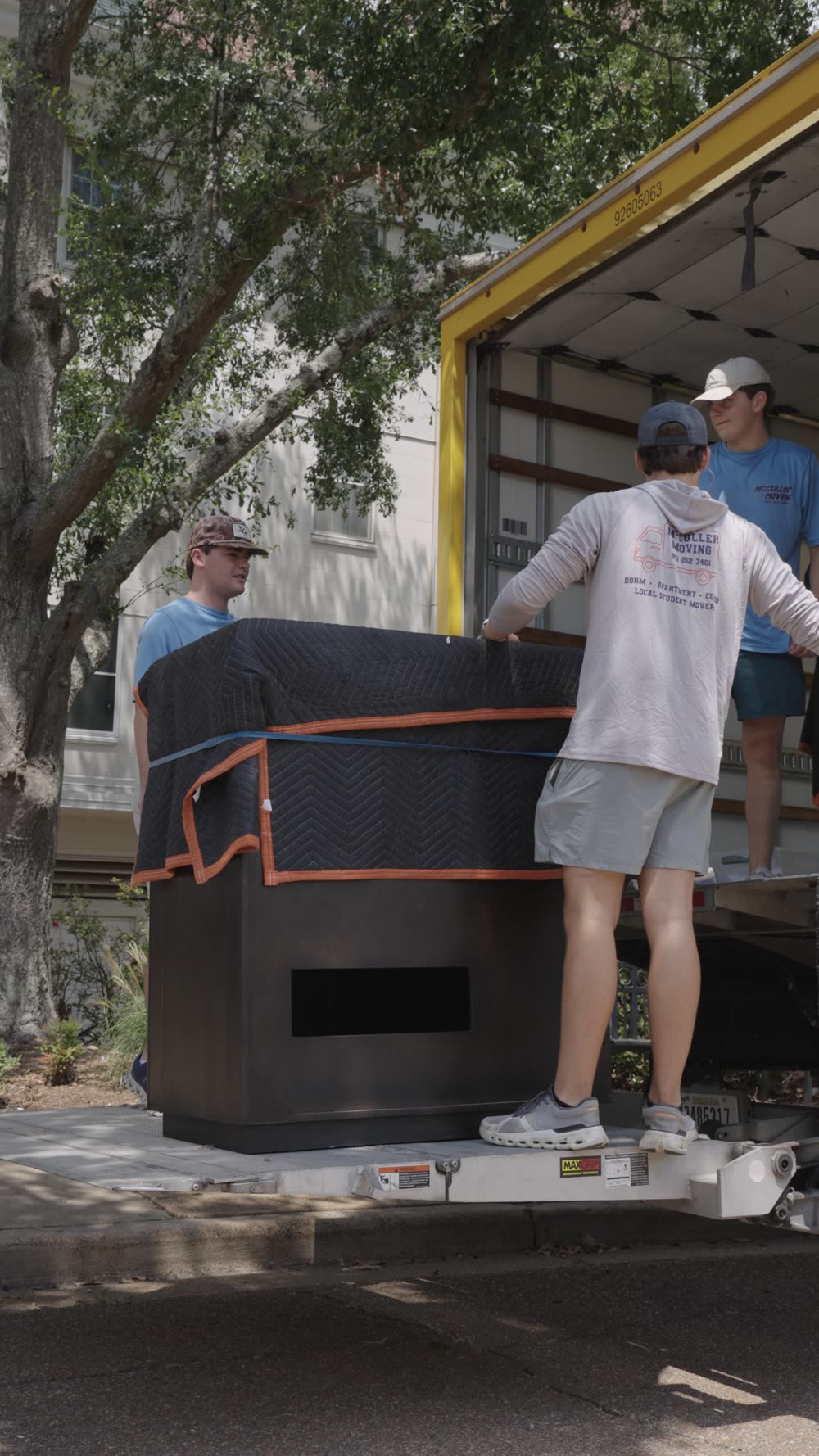 Two crew members loading a large item into the truck