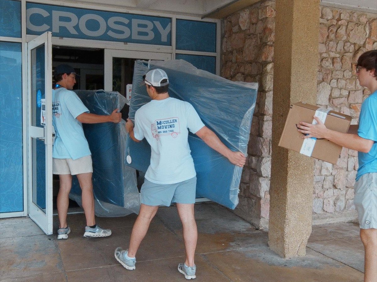 McCuller Moving crew carrying a new mattress and boxes through the doors of Crosby Hall on move-in day