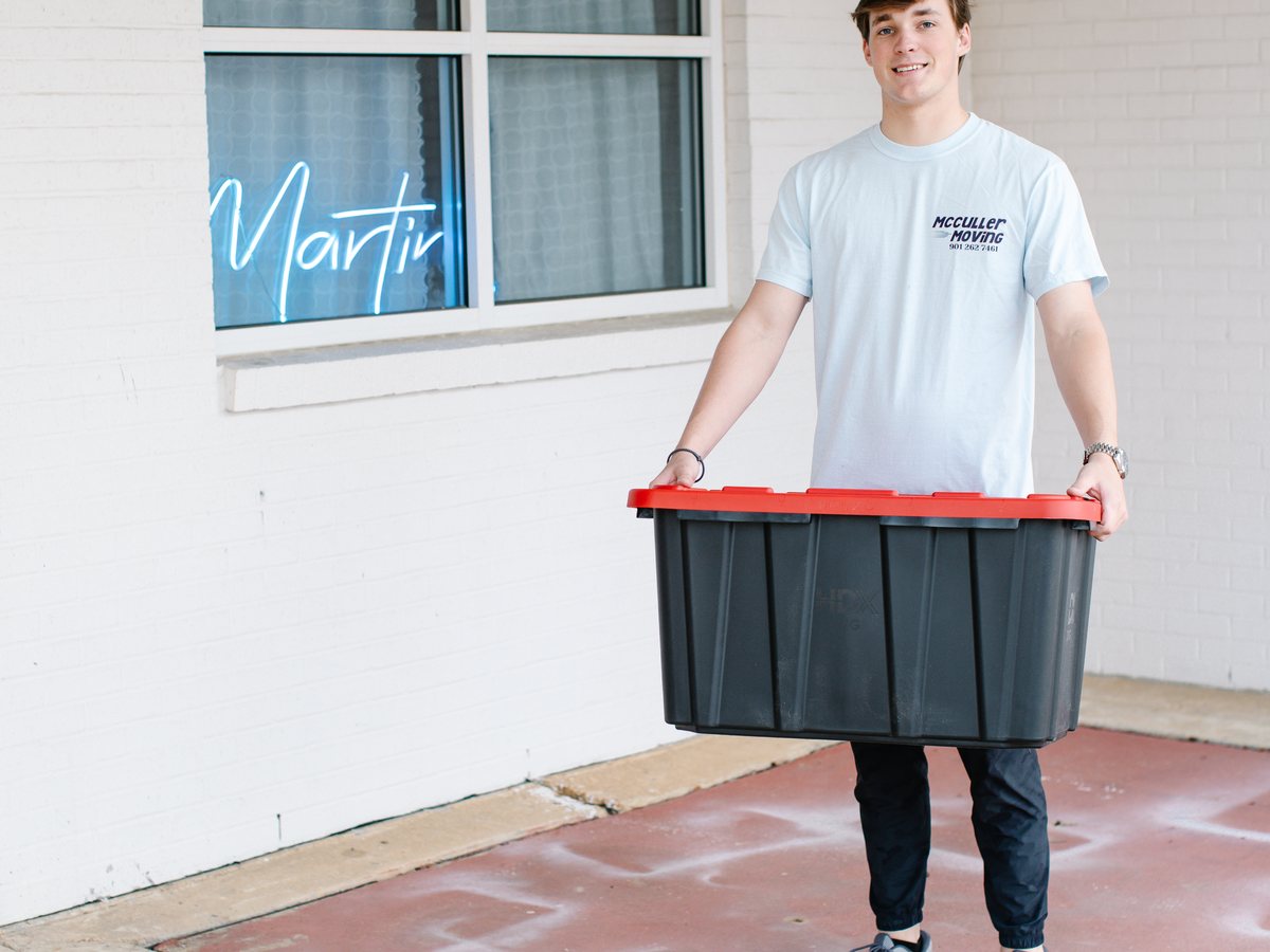 A McCuller Moving crew member carrying a student storage tote
